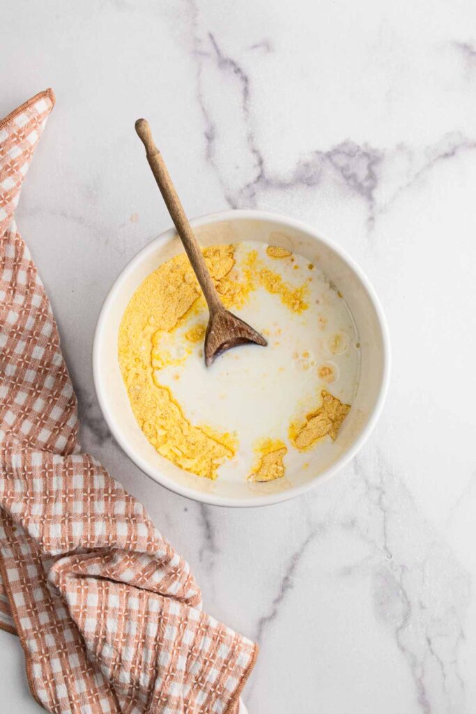 Adding wet ingredients to the hush puppy mixture.