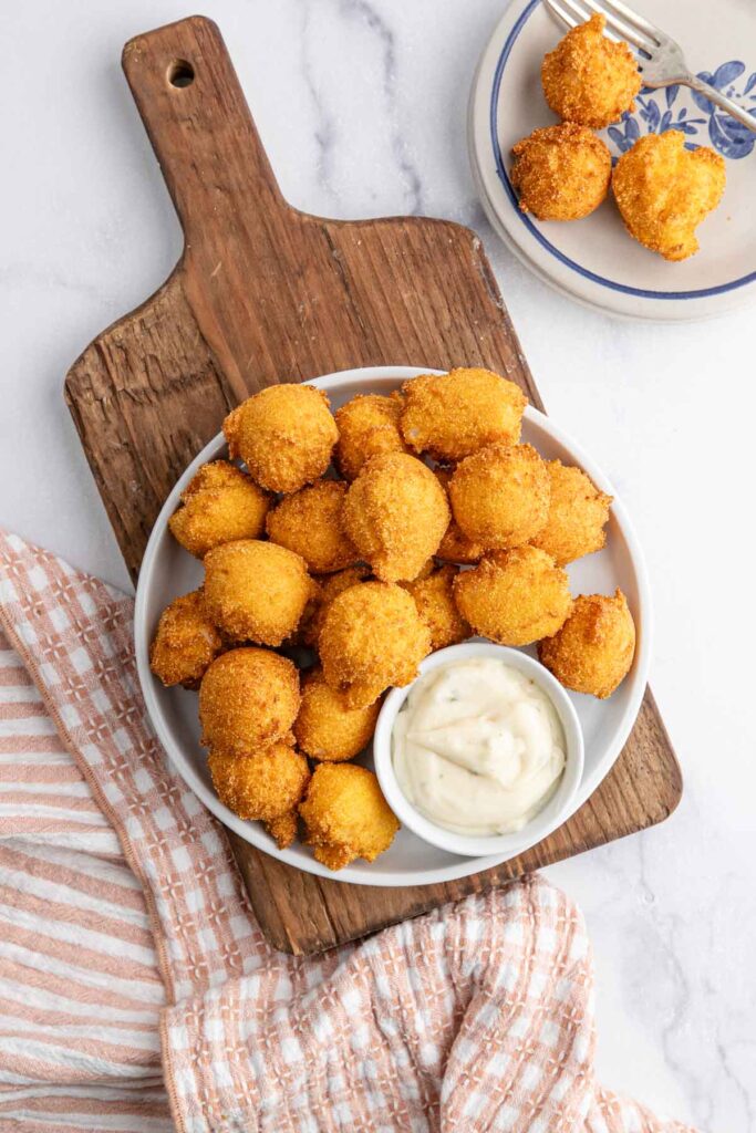 Overhead view of a plate of hush puppies with tarter sauce.