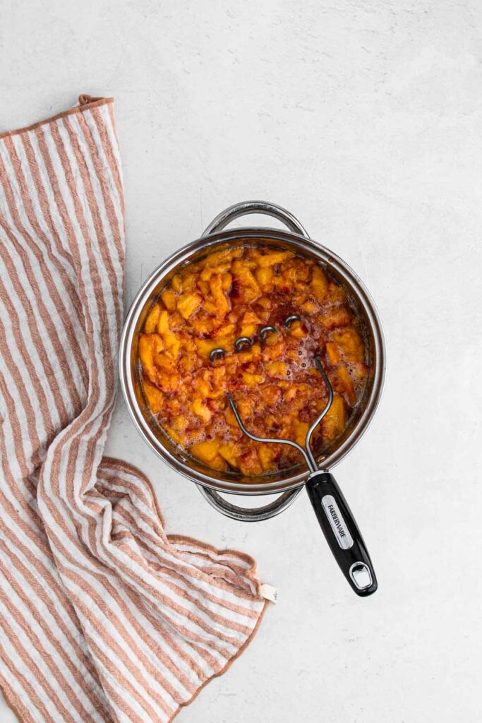 Mashing peaches in large pot.